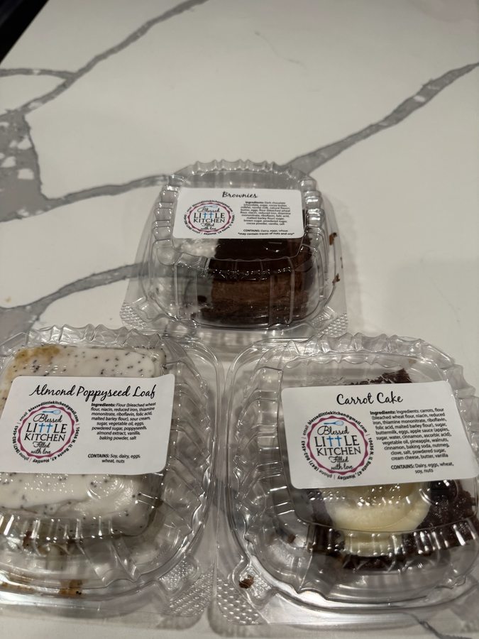 Individually packaged brownies, almond poppyseed loaf and carrot cake, each labeled with the Blessed Little Kitchen sticker