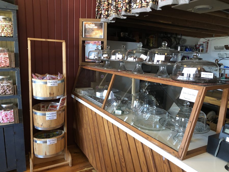 Sadie's display case with trays of fudge and chocolates, rock candy, and barrels of button candy.