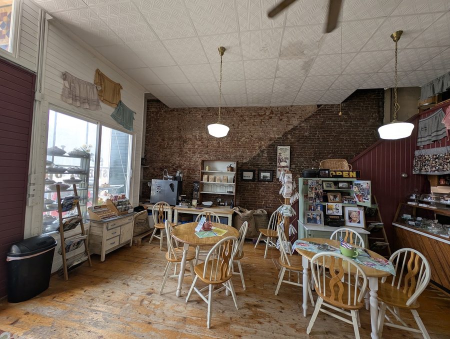 Inside Sadie's Sweet Shop — exposed brick wall, seating, and the pastry case by the counter.