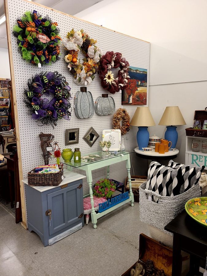 A wall of handmade wreaths and seasonal decor with painted furniture pieces