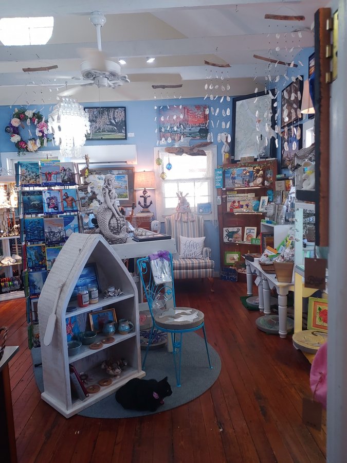 A cozy browsing nook with a mermaid statue, greeting-card racks, and gift baskets.