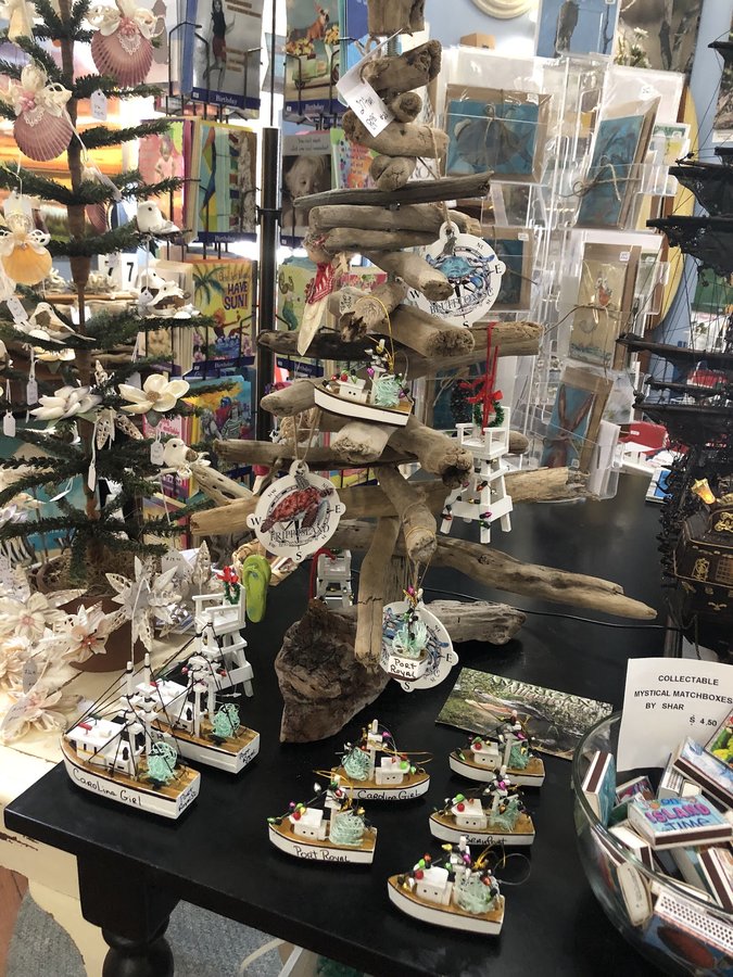 Handcrafted driftwood ornaments and small boat models on a display tree.