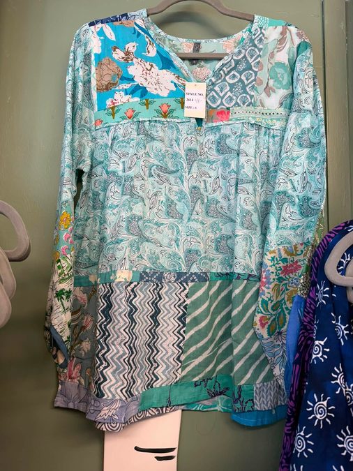 A bohemian patchwork tunic hanging on a clothing rack in the boutique