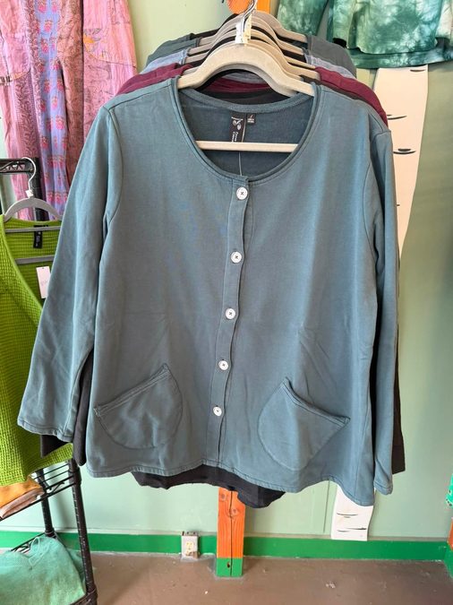 A teal cardigan on a rack against a colorful shop interior