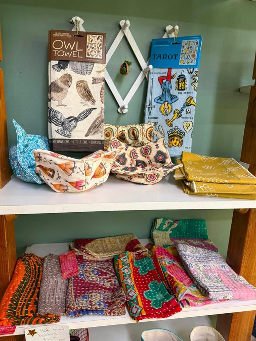 A gift shelf with dish towels, scarves and small home goods