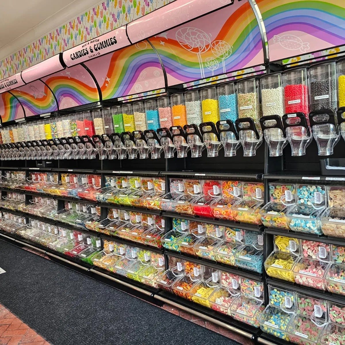 Bulk and gummy candy wall under a Candies and Gummies rainbow sign inside Sweet Spot Saugatuck